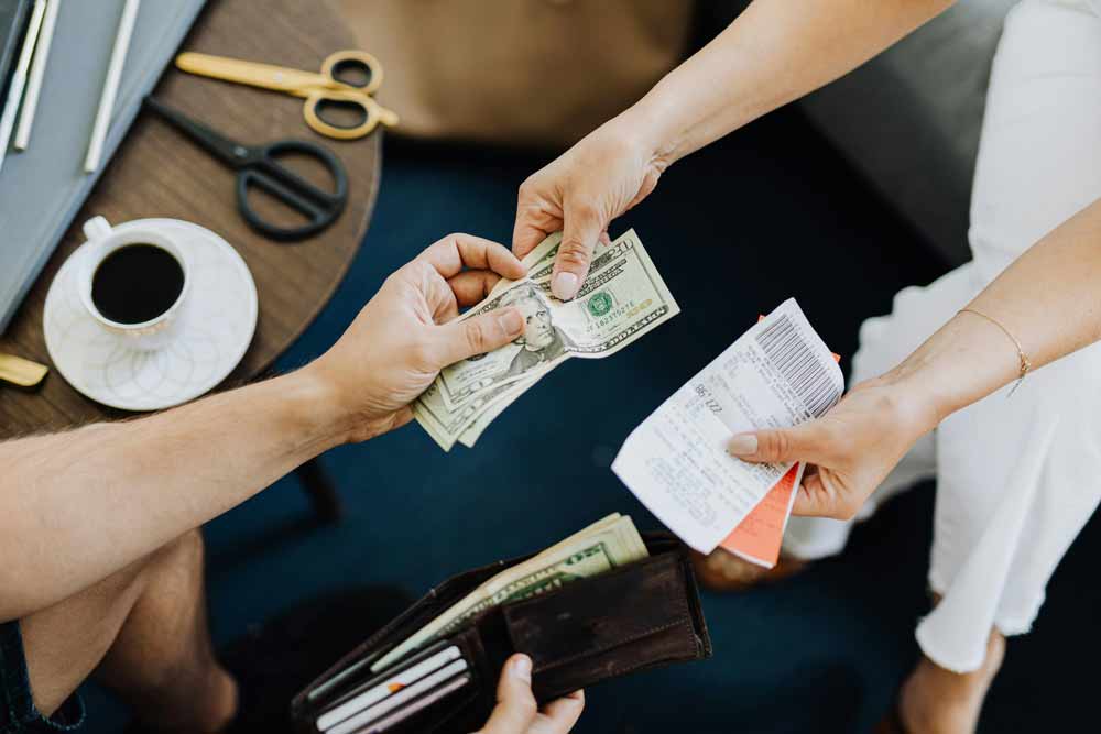 Hands exchanging cash and a receipt over a table