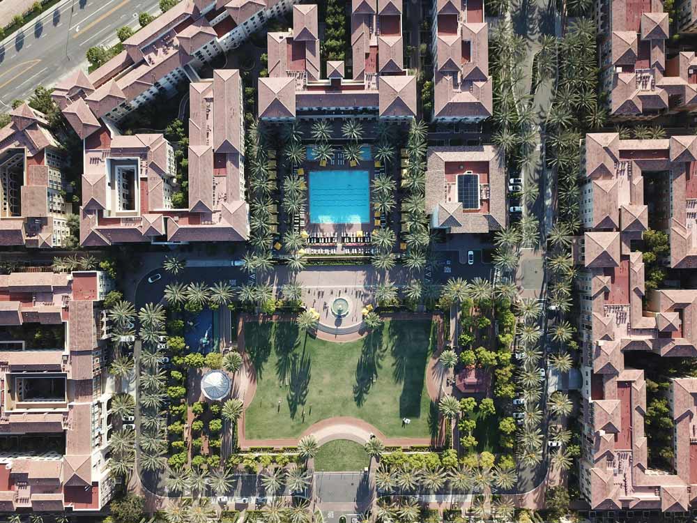 Aerial view of a residential complex around a central garden and pool