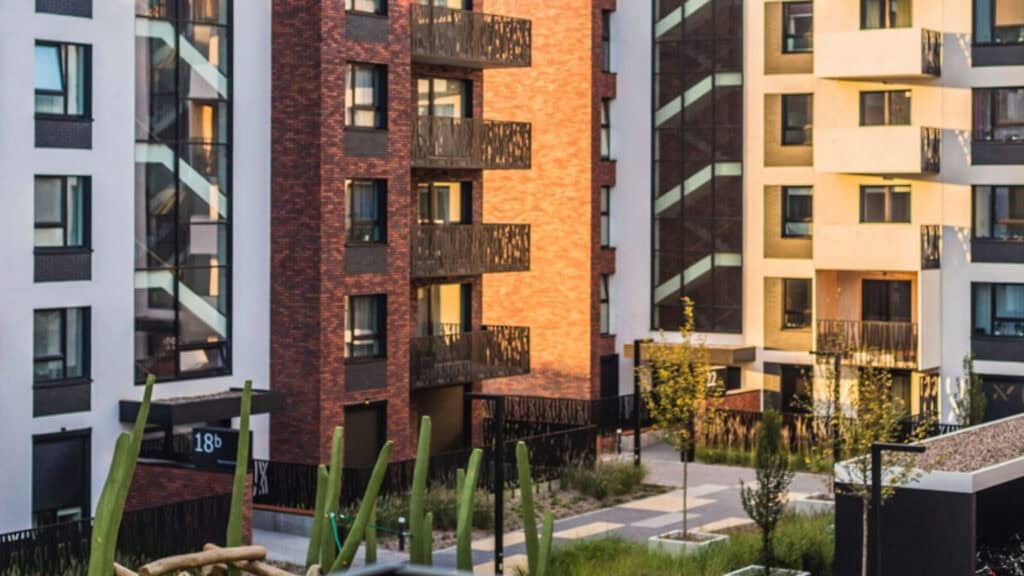 Apartment buildings in brick and orange around a planted courtyard