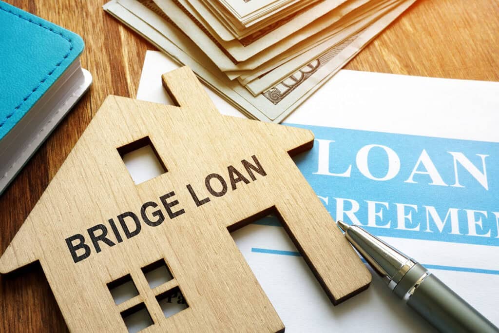 Wooden house cutout labelled Bridge Loan on a loan agreement