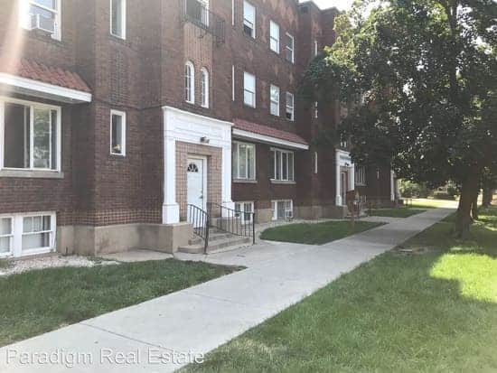 Brick apartment building with a tree-lined walkway