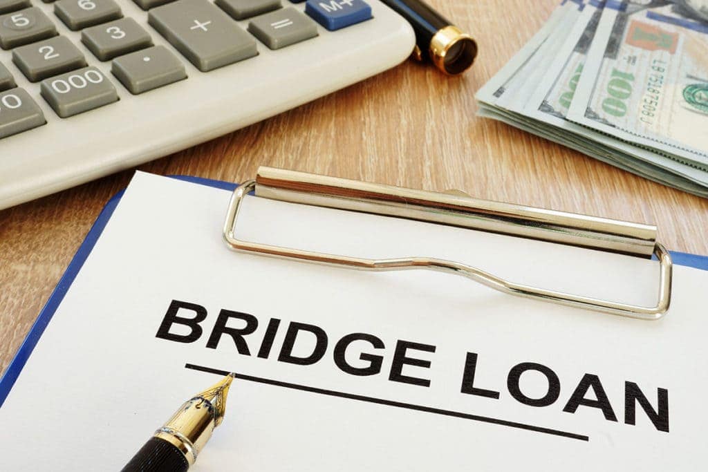 Clipboard labelled Bridge Loan beside a calculator and cash
