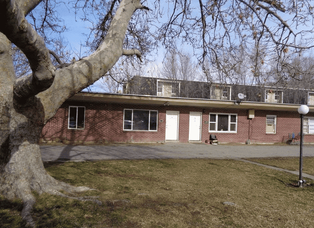 Low brick apartment building behind a large bare tree
