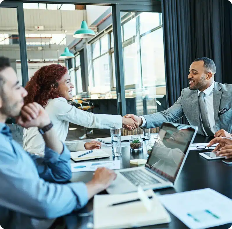 Colleagues shaking hands across a meeting table