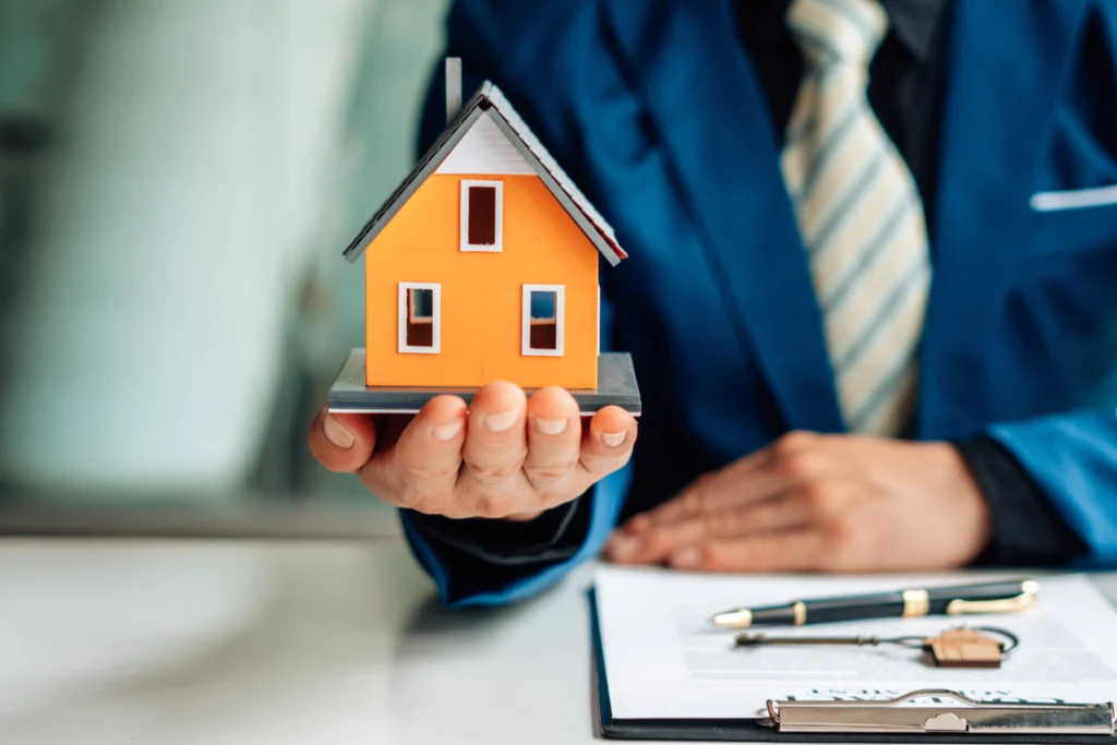 Person in a suit holding an orange model house