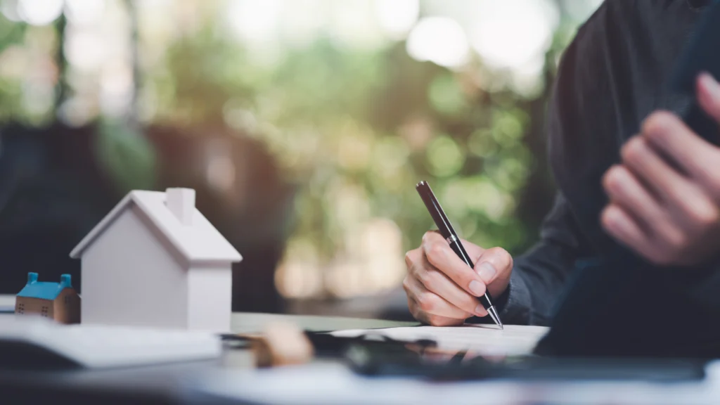 Person writing beside a white model house
