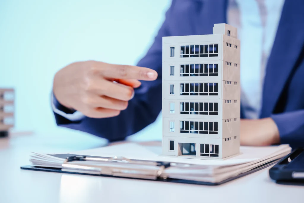 Hand pointing at a model apartment building on a desk