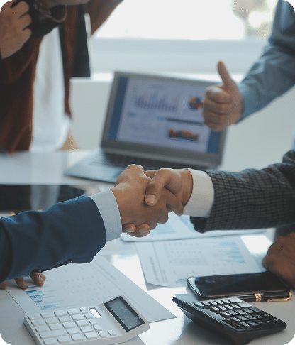 Handshake over a desk with a tablet and calculators
