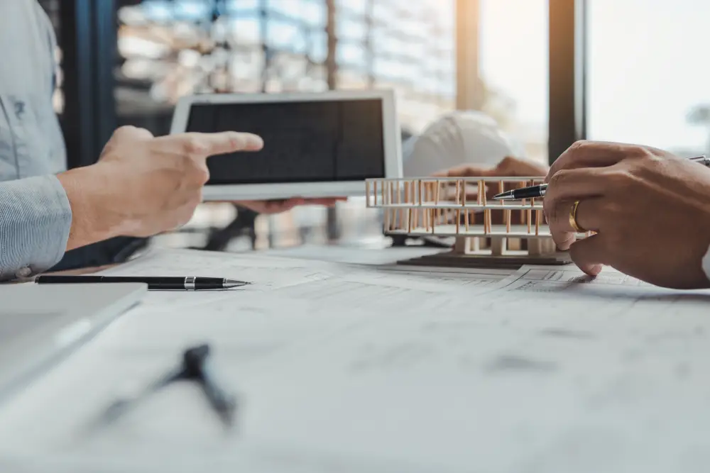 Hands pointing at a tablet over architectural drawings