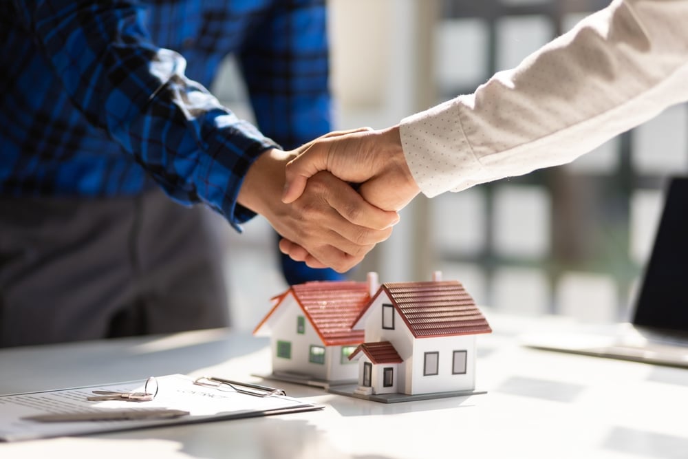 Handshake above model houses on a desk