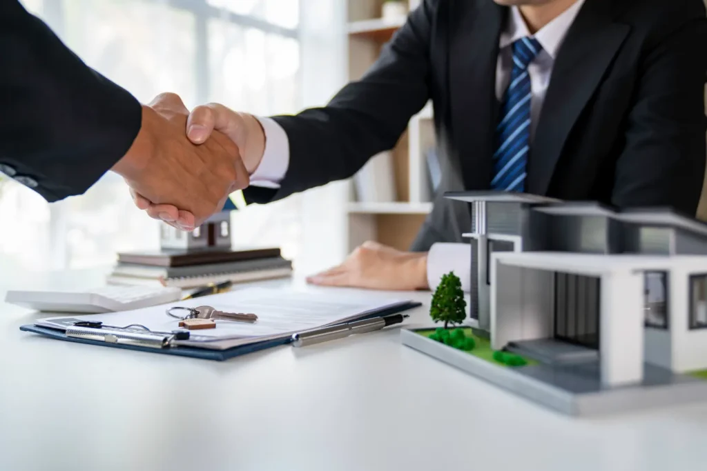 Handshake over a contract beside a model house