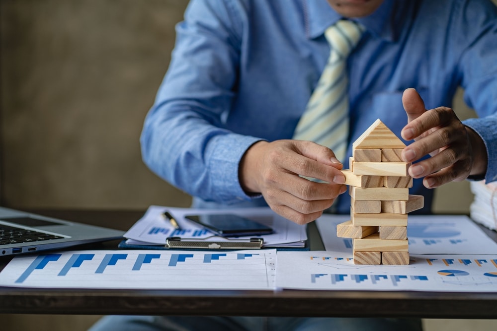 Hands stacking wooden blocks into a tower over charts