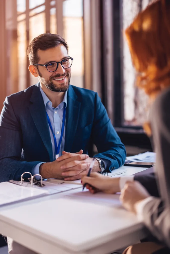 Smiling man in glasses talking with a client across a desk