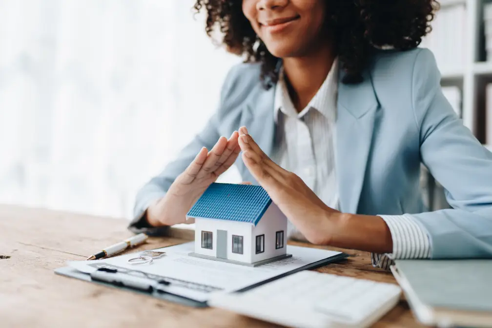 Woman holding her hands over a model house like a roof
