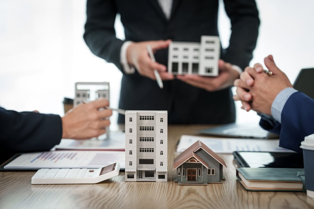 People discussing model buildings across a desk