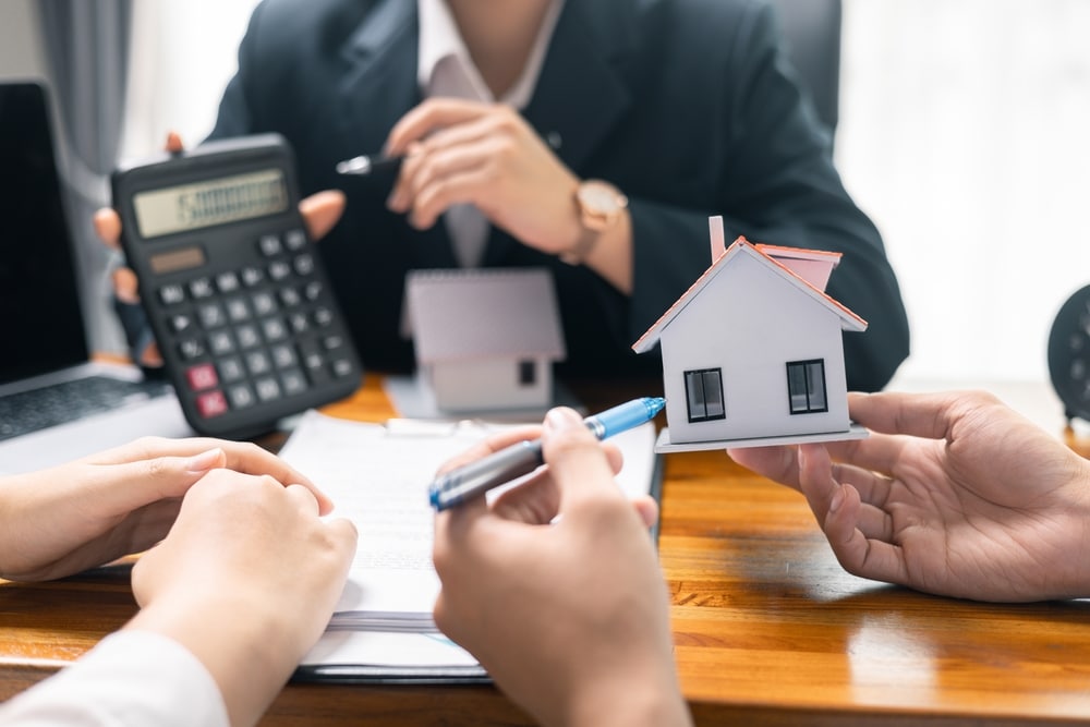 People with a calculator and a model house at a desk
