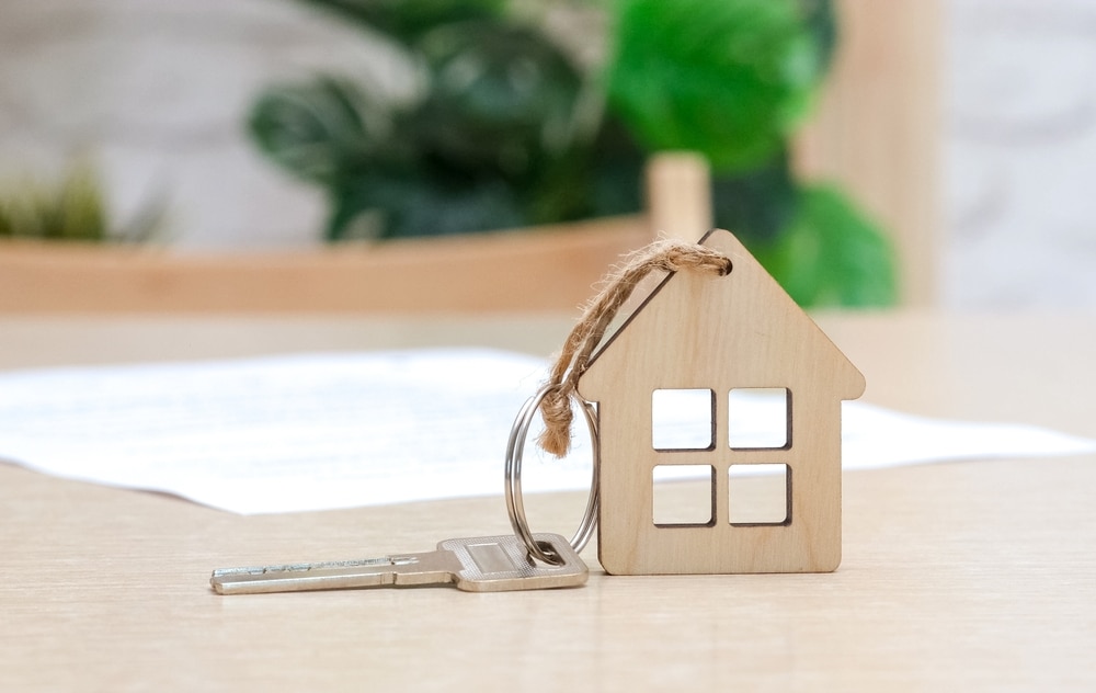 House-shaped wooden key ring with keys on a table