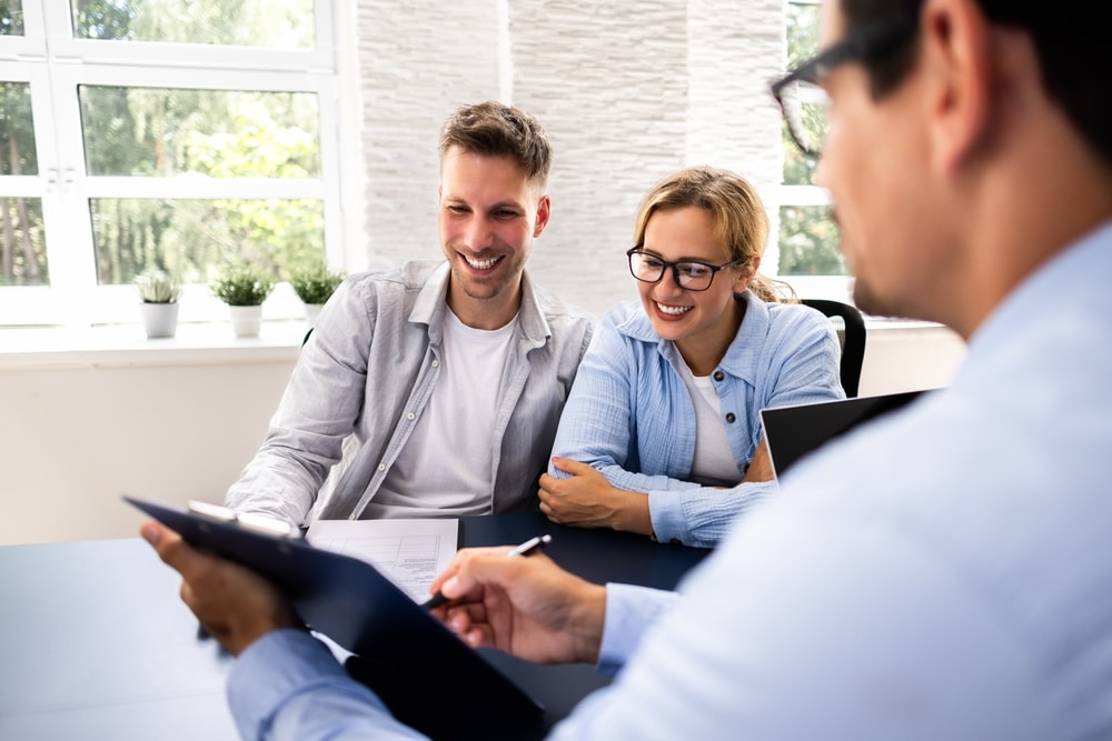 Couple talking with an adviser holding a clipboard