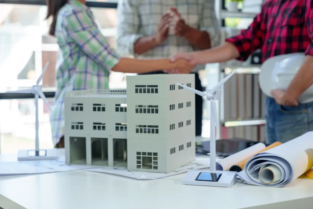 Handshake over a model building and rolled plans
