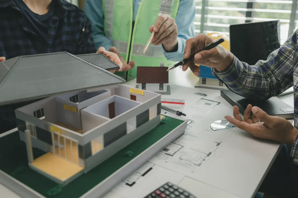 People pointing at a floor-plan model on a table