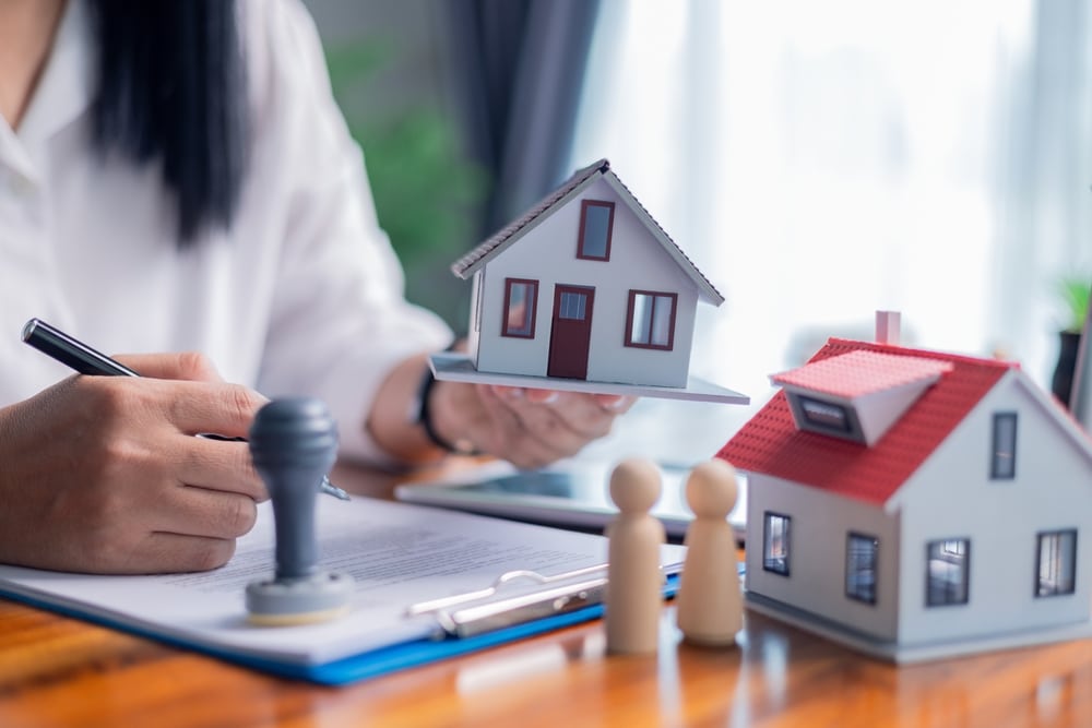 Person stamping paperwork beside model houses
