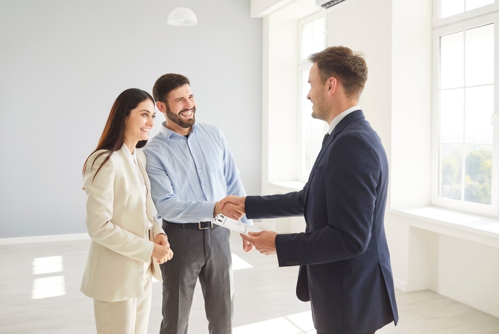 Couple shaking hands with a man in a suit in a bright room