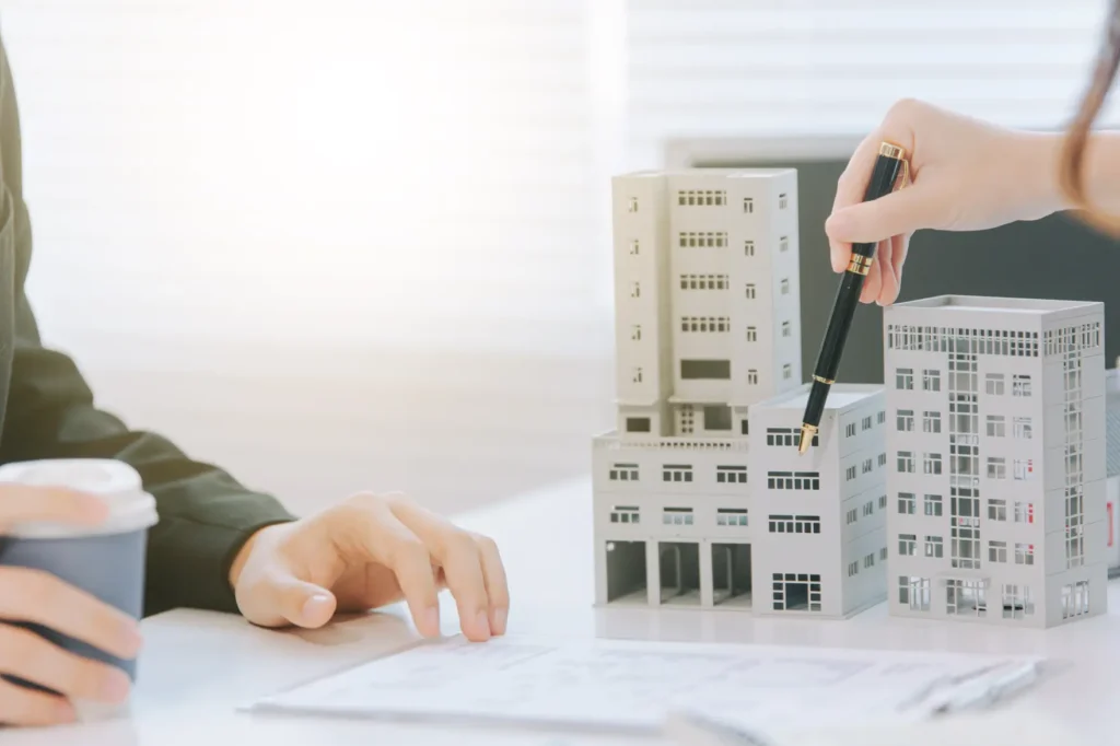 Hand touching a model apartment building on a desk