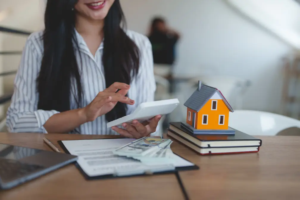Woman using a tablet beside a model house and books
